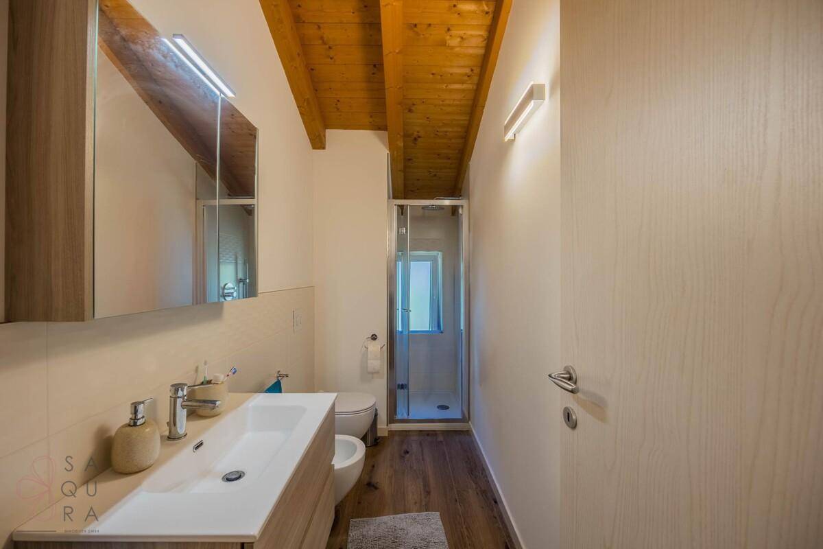 Modernes Badezimmer mit Einzelwaschbecken, Duschkabine und Holzbalkendecke.