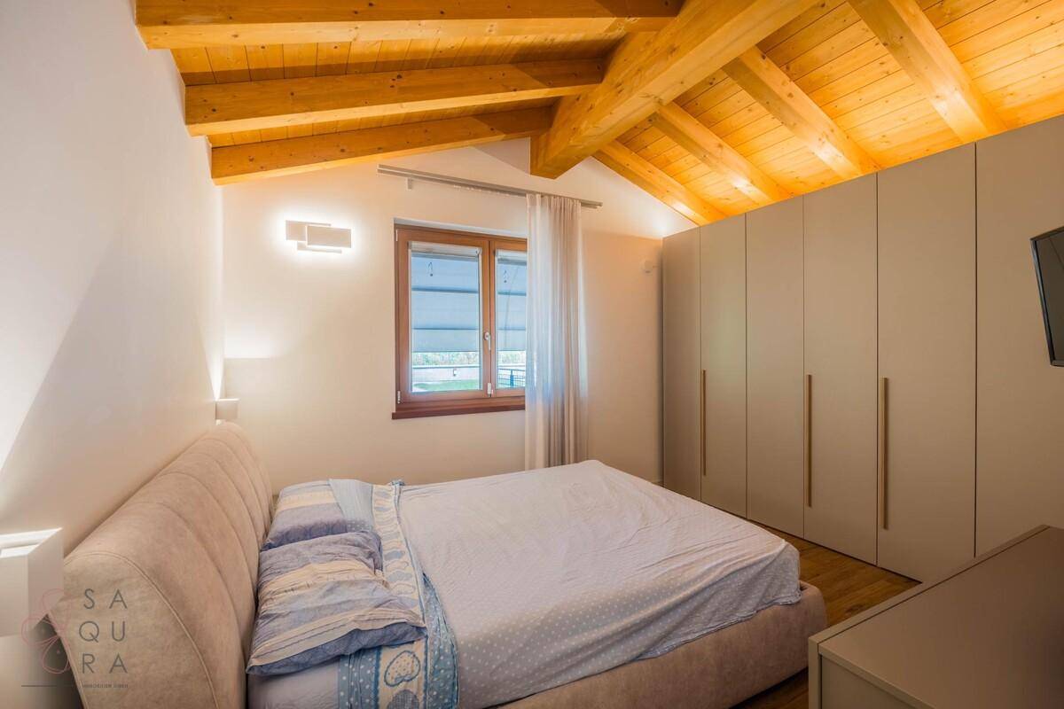 Modernes Schlafzimmer mit Doppelbett, Einbauschränken und Holzbalkendecke.