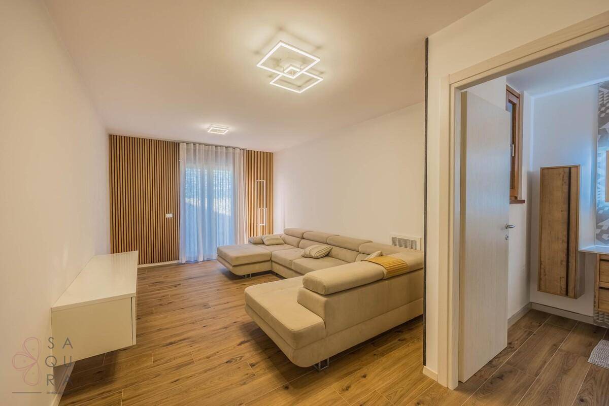 Gemütliches Wohnzimmer mit großem Ecksofa, Holzpaneelwand und modernem Lichtdesign.