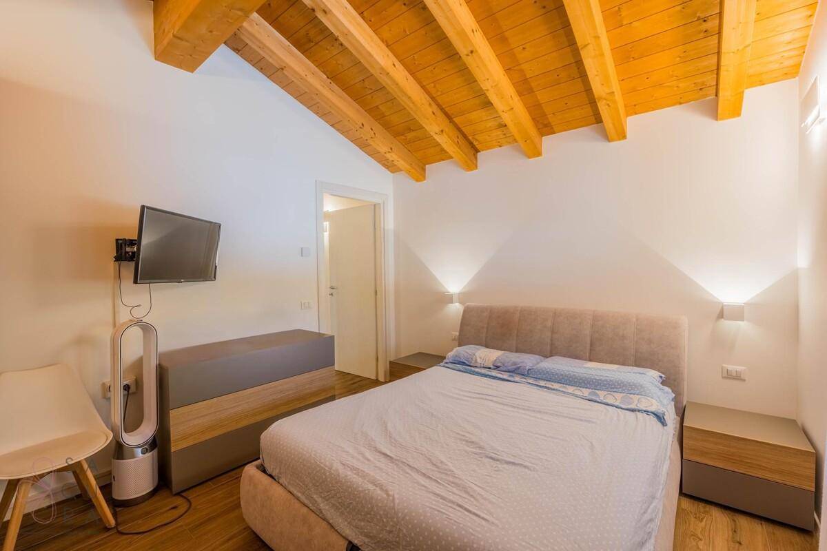 Gemütliches Schlafzimmer mit Doppelbett, Holzbalkendecke und Wandleuchten.