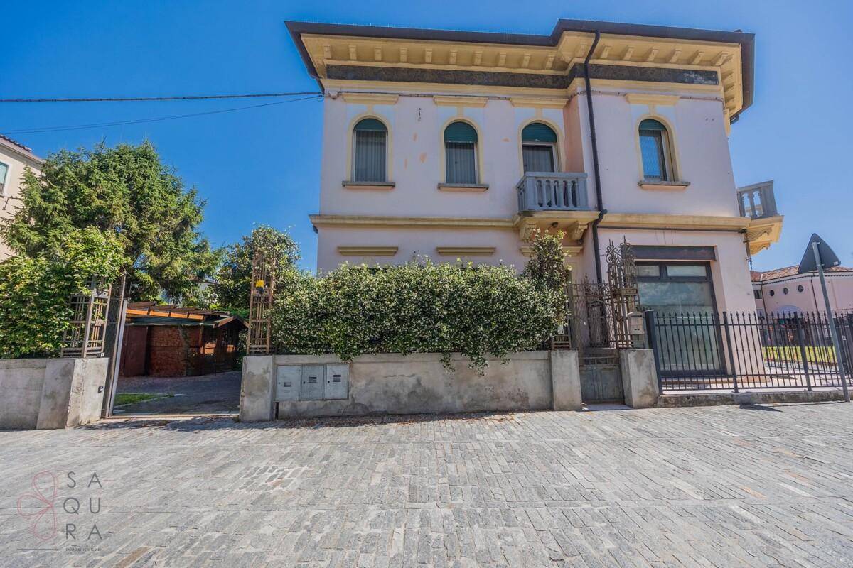 Vorderansicht der Villa mit eleganter Fassade, schmiedeeisernem Tor und gepflastertem Zugang.