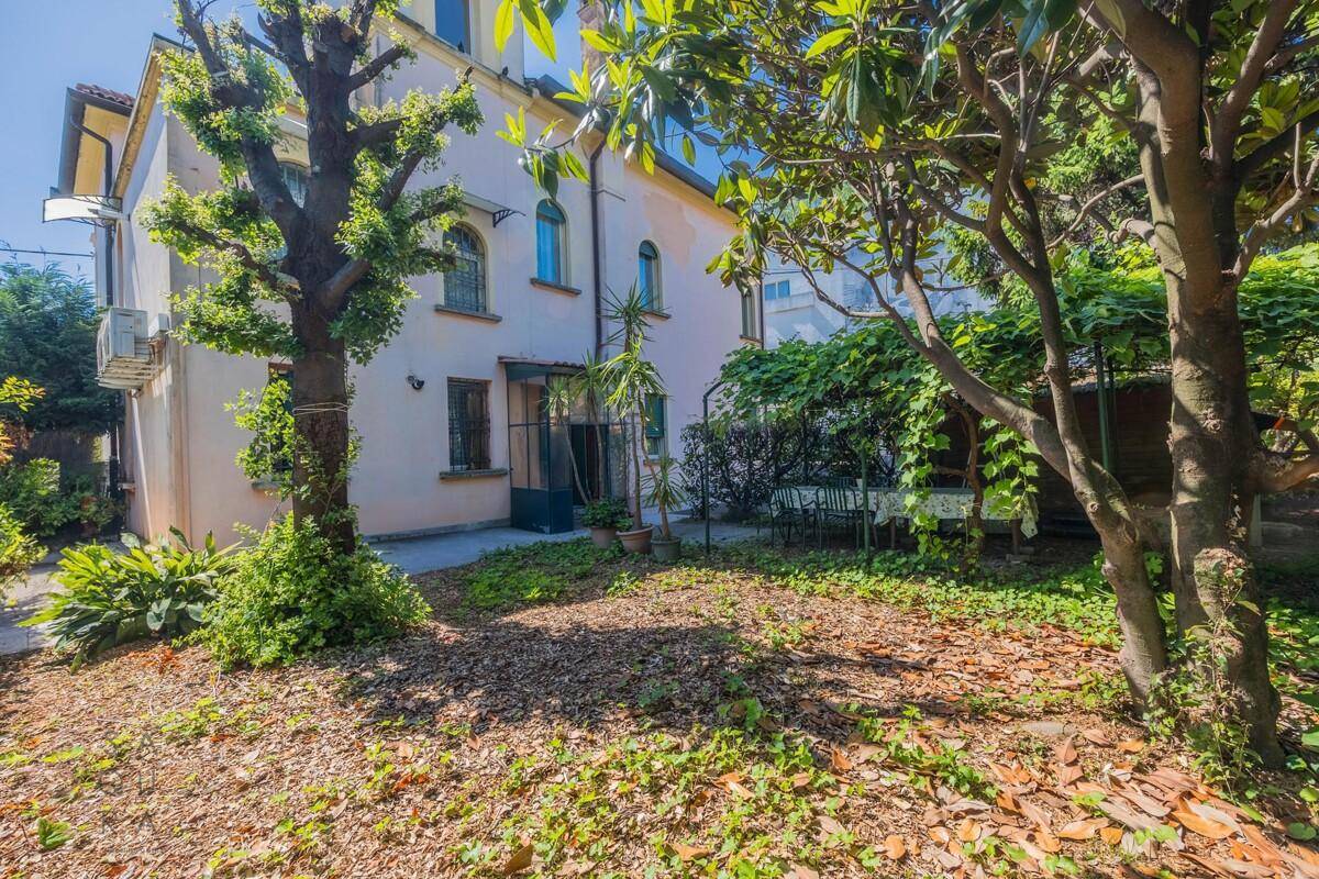 Rückseite der Villa mit weitläufigem Garten, üppiger Vegetation und einem gemütlichen Sitzbereich.