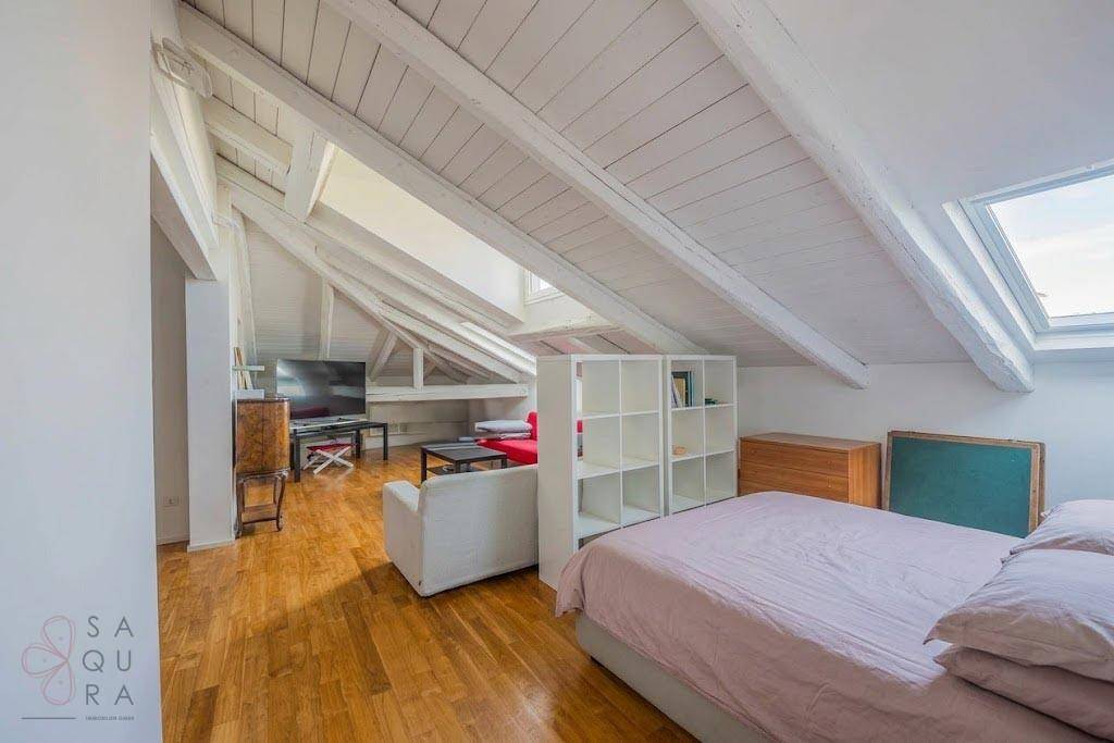 Gemütlicher Dachbodenbereich mit Holzbalken, Schlafbereich und Wohnbereich unter Dachschrägen.