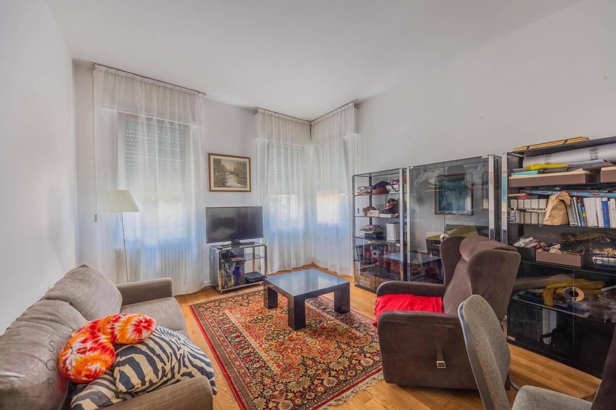 Gemütliches Wohnzimmer mit Sofa, Sessel, Fernseher und einem orientalischen Teppich.
