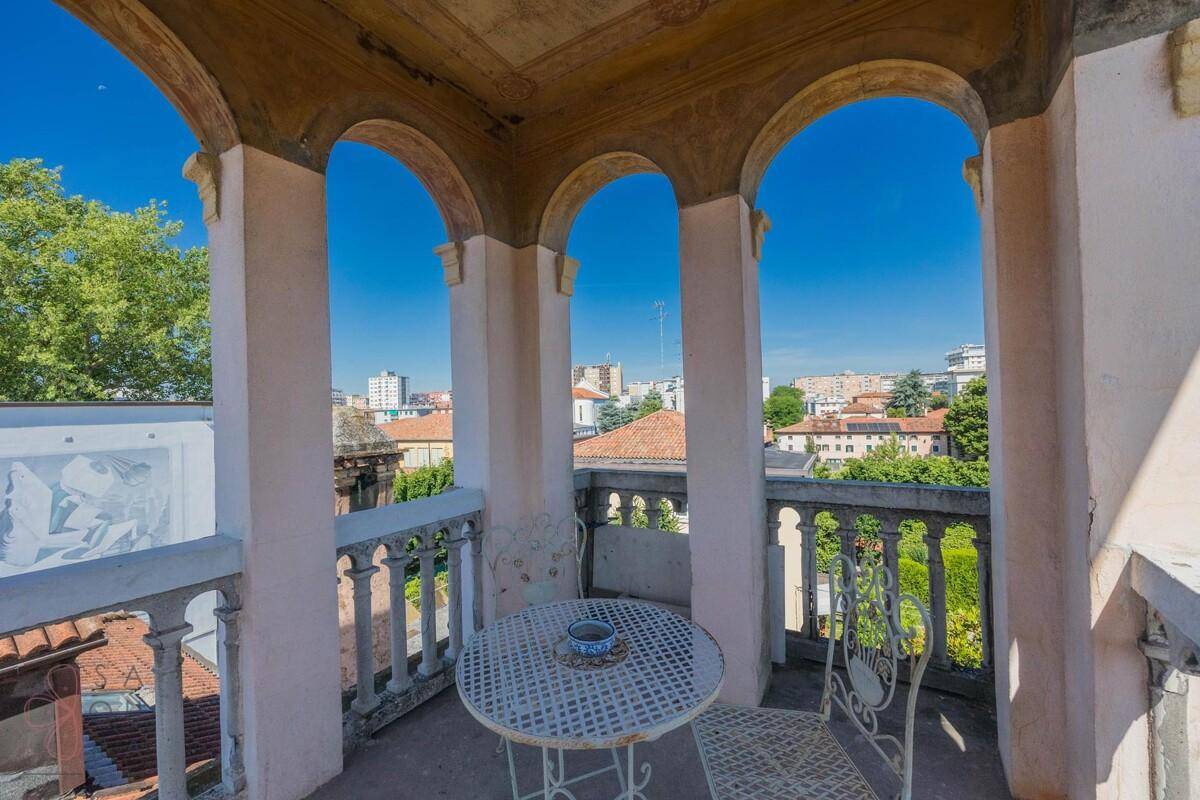 Historischer Balkon mit Bögen, schmiedeeisernen Möbeln und Blick über die Stadt.