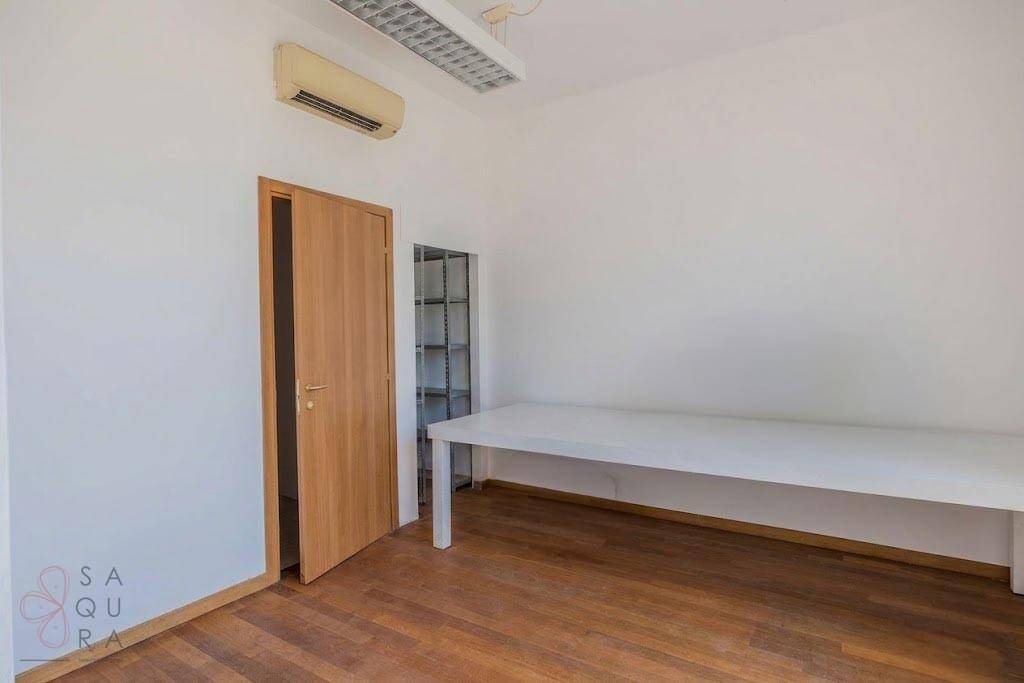 Heller Raum mit Holzboden, Klimaanlage und einfacher Einrichtung, ideal als Büro.