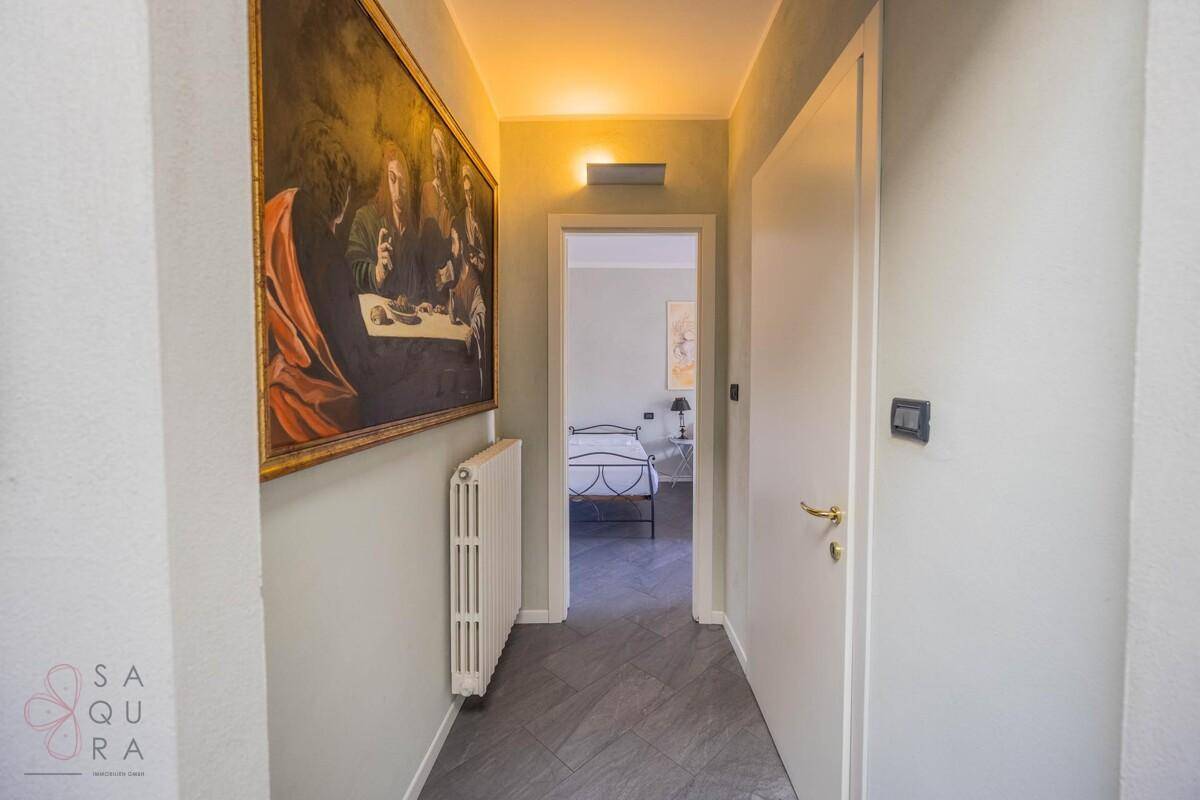 Heller Flur mit großem Gemälde an der Wand und Zugang zu den Schlafzimmern.