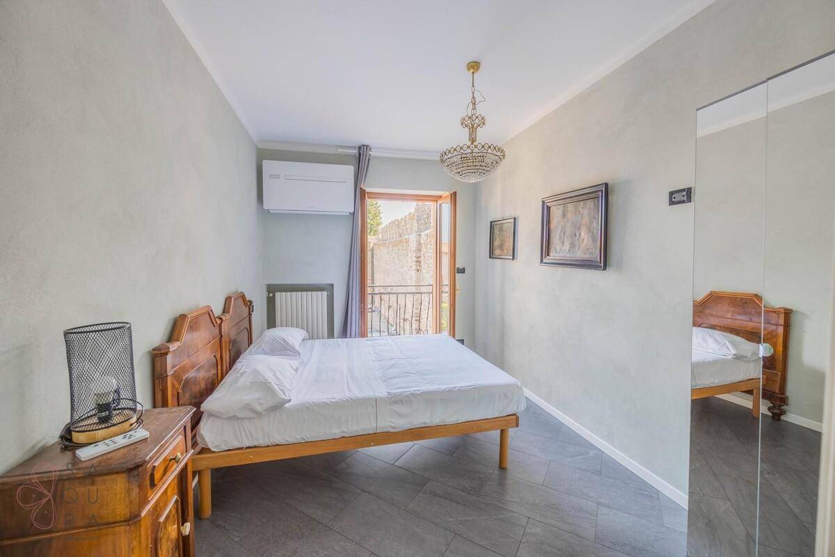 Helles Schlafzimmer mit Holzbett, Nachttisch und direktem Zugang zum Balkon.