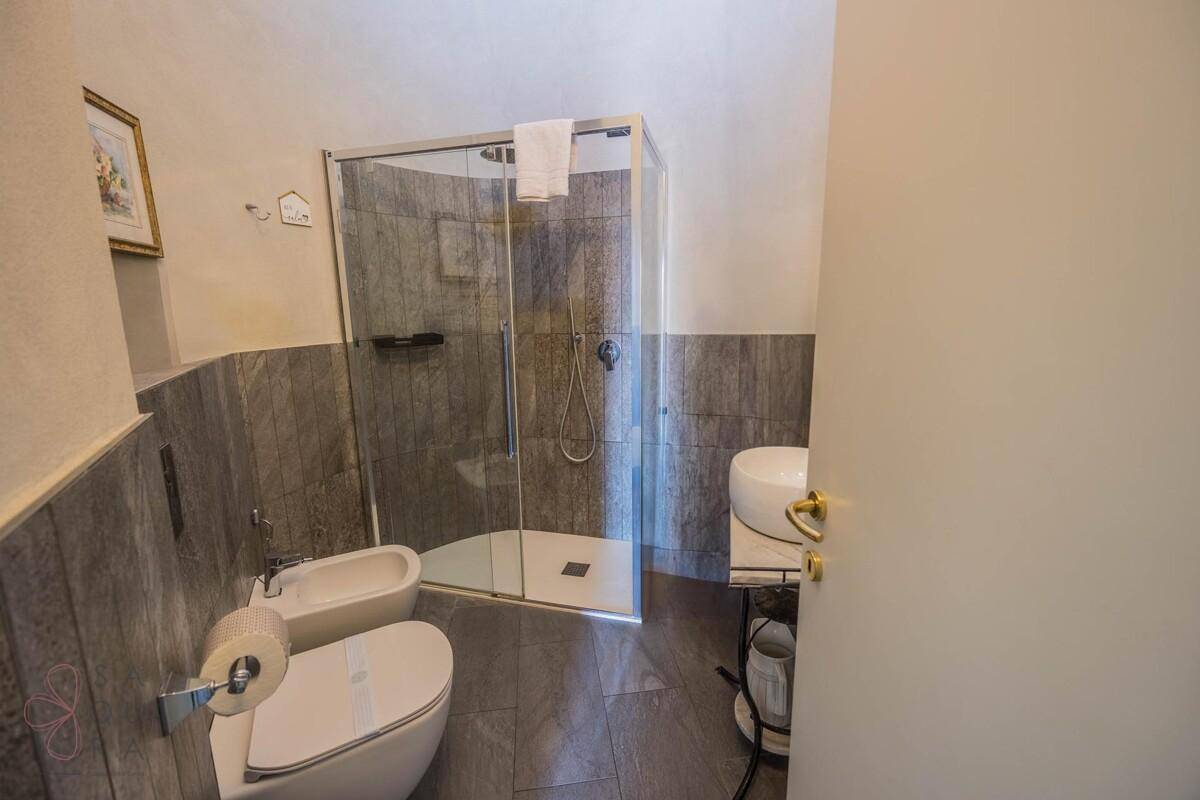 Modernes Badezimmer mit Duschkabine, Toilette, Bidet und einem einzelnen Waschbecken.