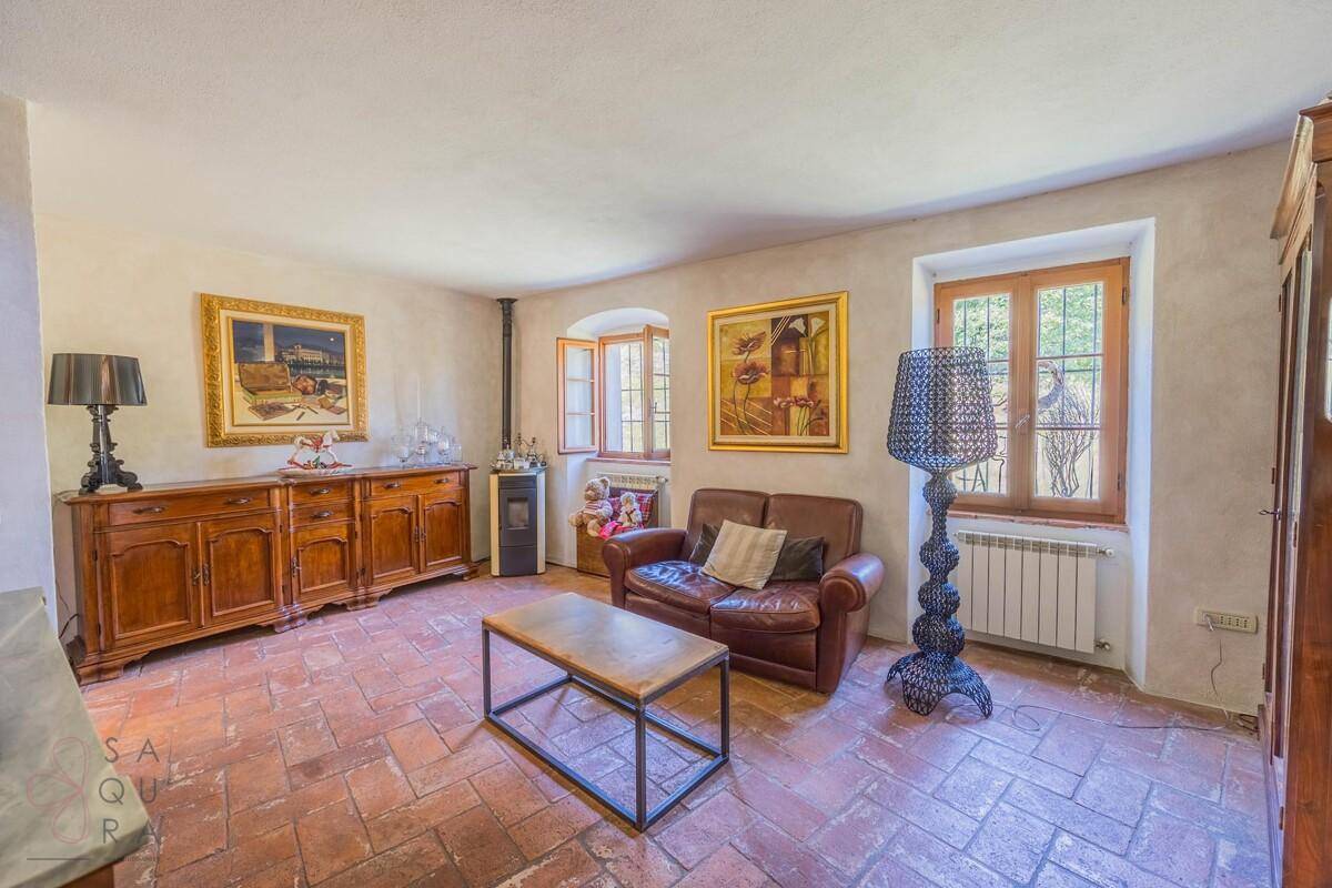 Helles Wohnzimmer mit Ledersofa, Terrakottaboden und einem modernen Holzofen.