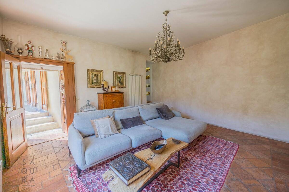 Helles Wohnzimmer mit Terrakottaboden, großem Sofa und elegantem Kronleuchter.