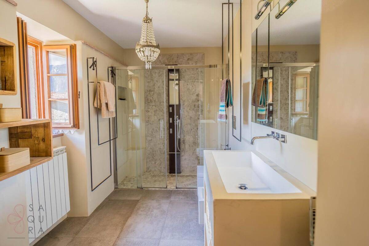 Modernes Badezimmer mit großer Dusche, Doppelwaschbecken und elegantem Kronleuchter.