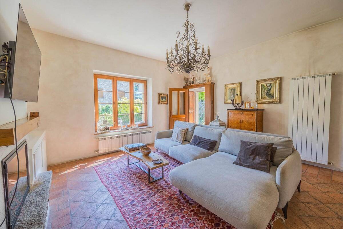 Gemütliches Wohnzimmer mit Terrakottaboden, bequemer Couch und klassischem Kronleuchter.