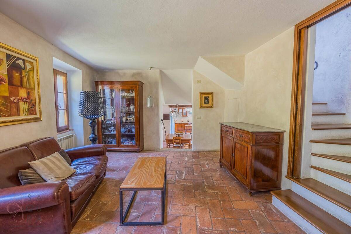 Gemütliches Wohnzimmer mit Ledersofa, Terrakottaboden und Blick auf die Treppe.