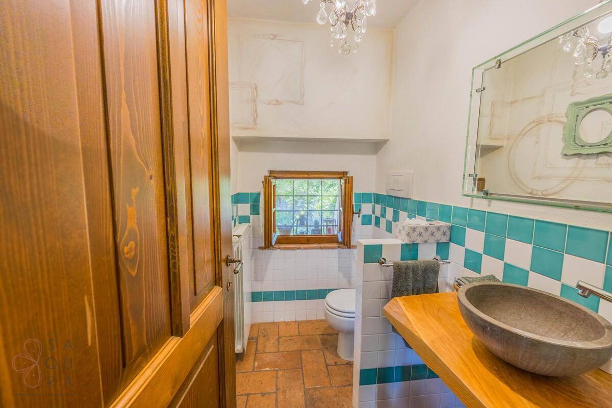 Kleines Gäste-WC mit Terrakottaboden, Holzwaschtisch und Fenster.