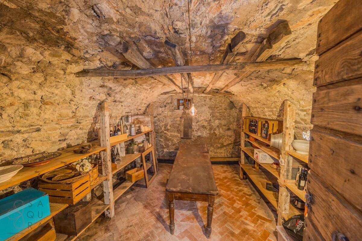 Historischer Kellerraum mit Steinwänden, Holzbalken und Regalen für Lagerung.