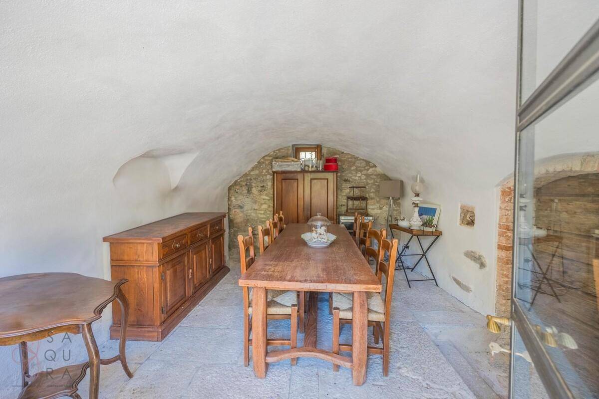 Rustikaler Essbereich im Kellergewölbe mit langem Holztisch und Steinwänden.