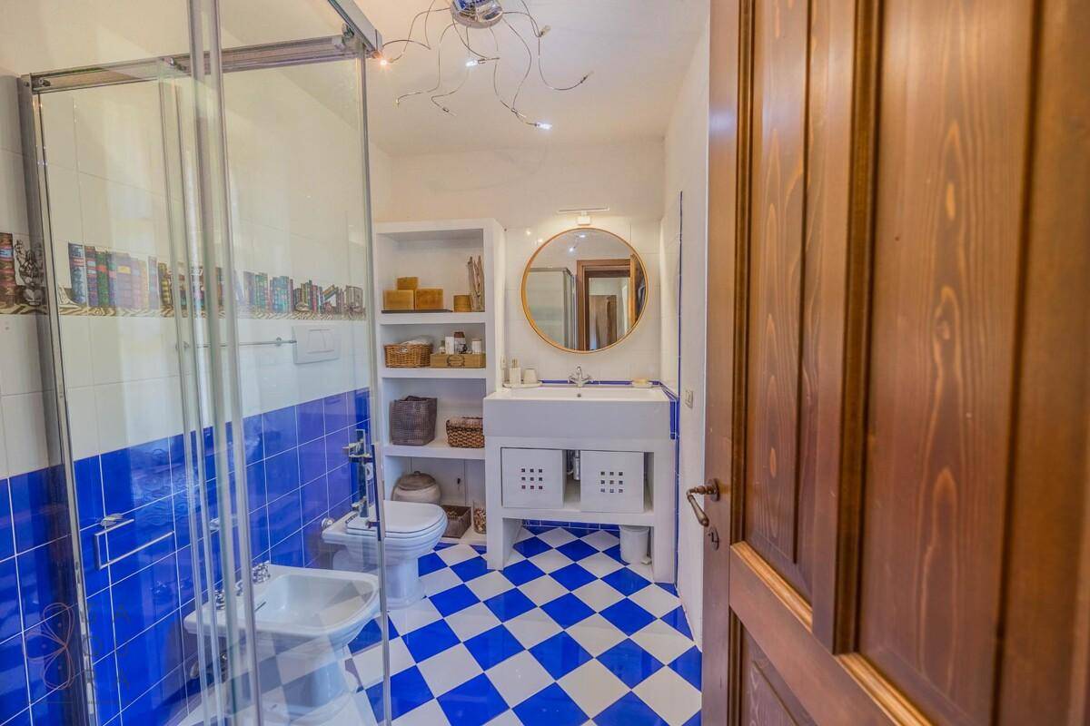 Farbenfrohes Badezimmer mit blau-weiß karierten Fliesen, Dusche und Bidet.