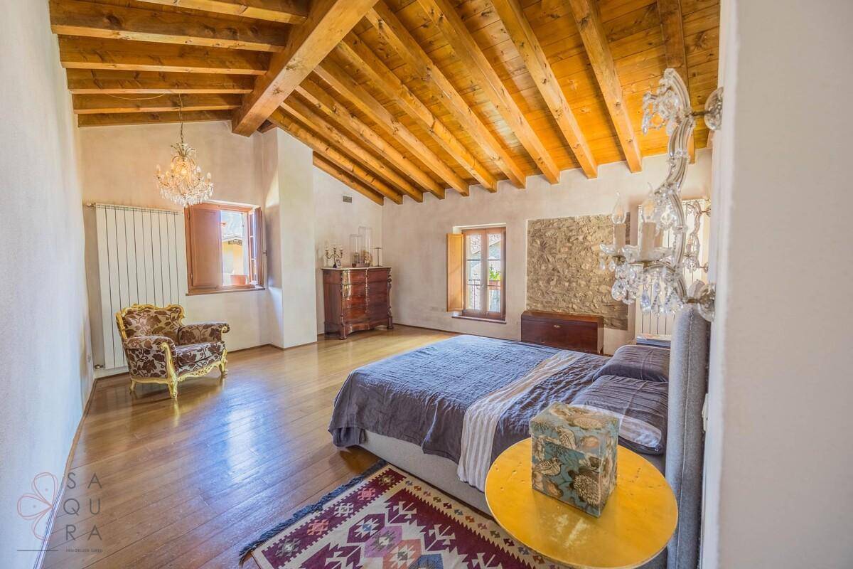 Geräumiges Schlafzimmer mit Holzbalkendecke, Holzboden und traditionellem Kronleuchter.