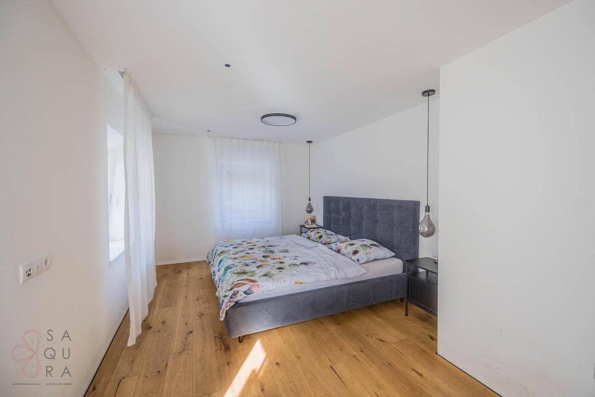 Geräumiges Schlafzimmer mit warmem Holzboden und viel Tageslicht, ideal zum Entspannen.
