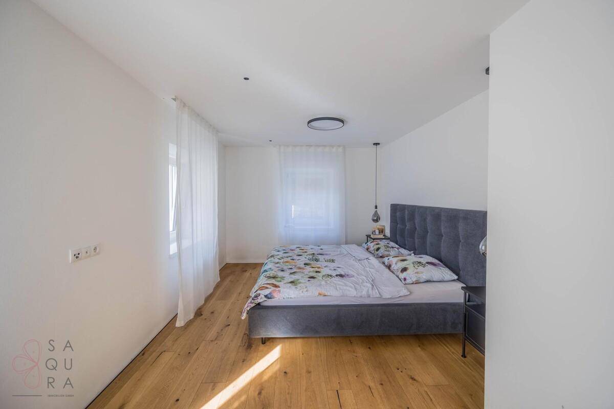 Helles Schlafzimmer mit Holzboden, großem Bett und Vorhängen für Privatsphäre.