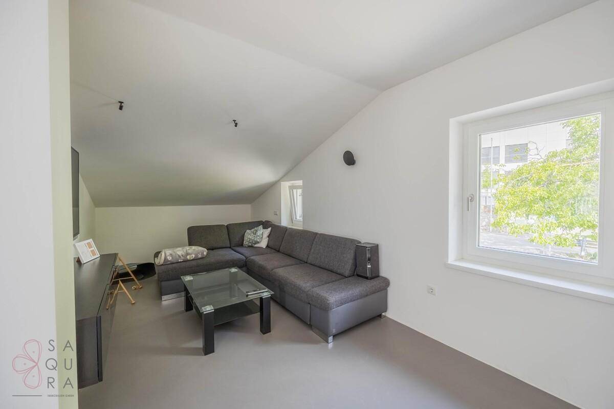 Gemütliches Wohnzimmer mit großem Ecksofa, Couchtisch und Fenster mit Blick nach draußen.