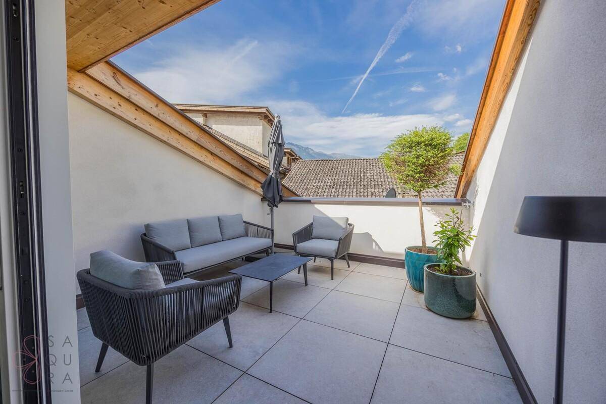 Geräumige Dachterrasse mit modernen Loungemöbeln und Blick auf die umliegende Landschaft.