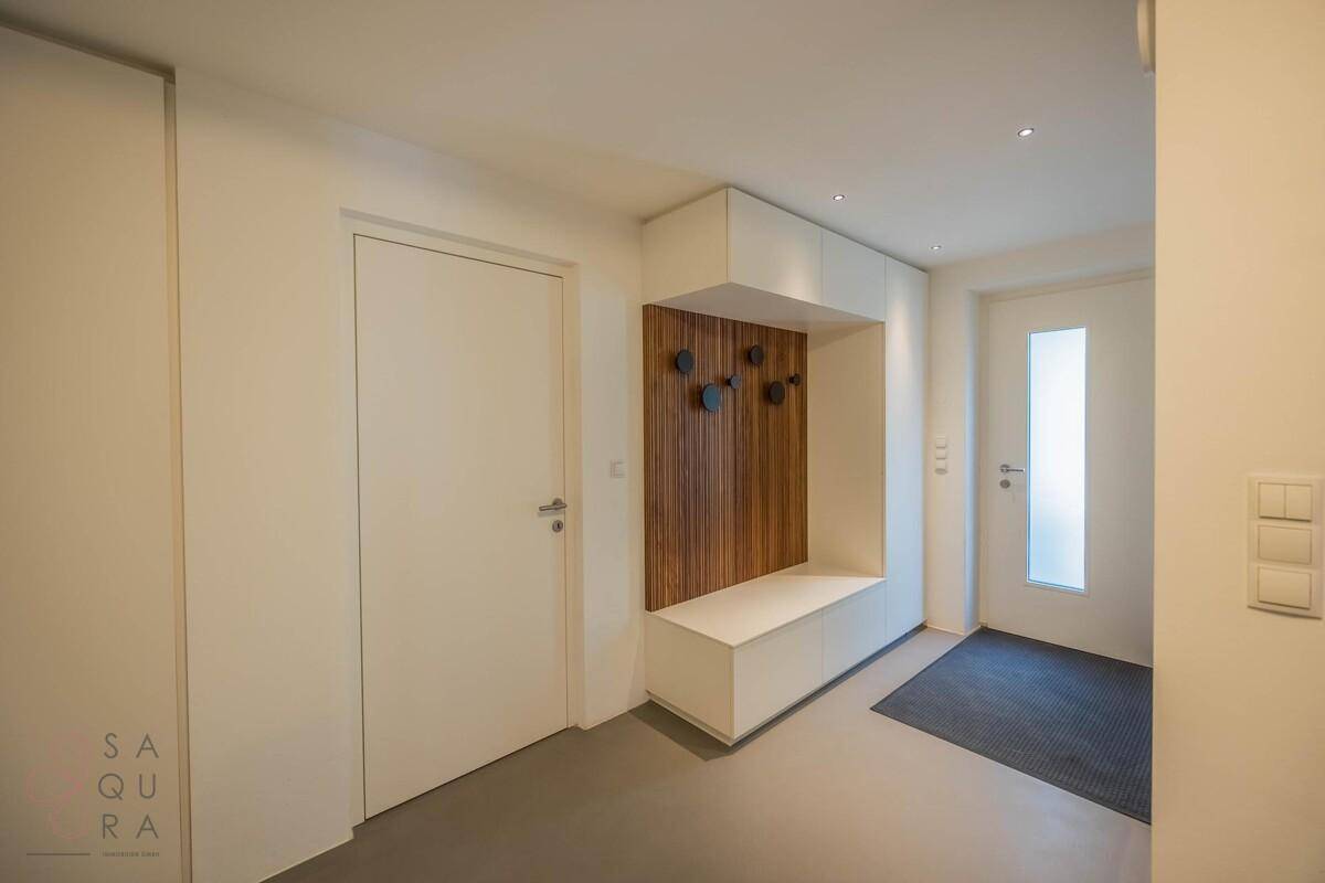 Moderner Eingangsbereich mit integrierter Garderobe und Sitzbank, hell und einladend gestaltet.