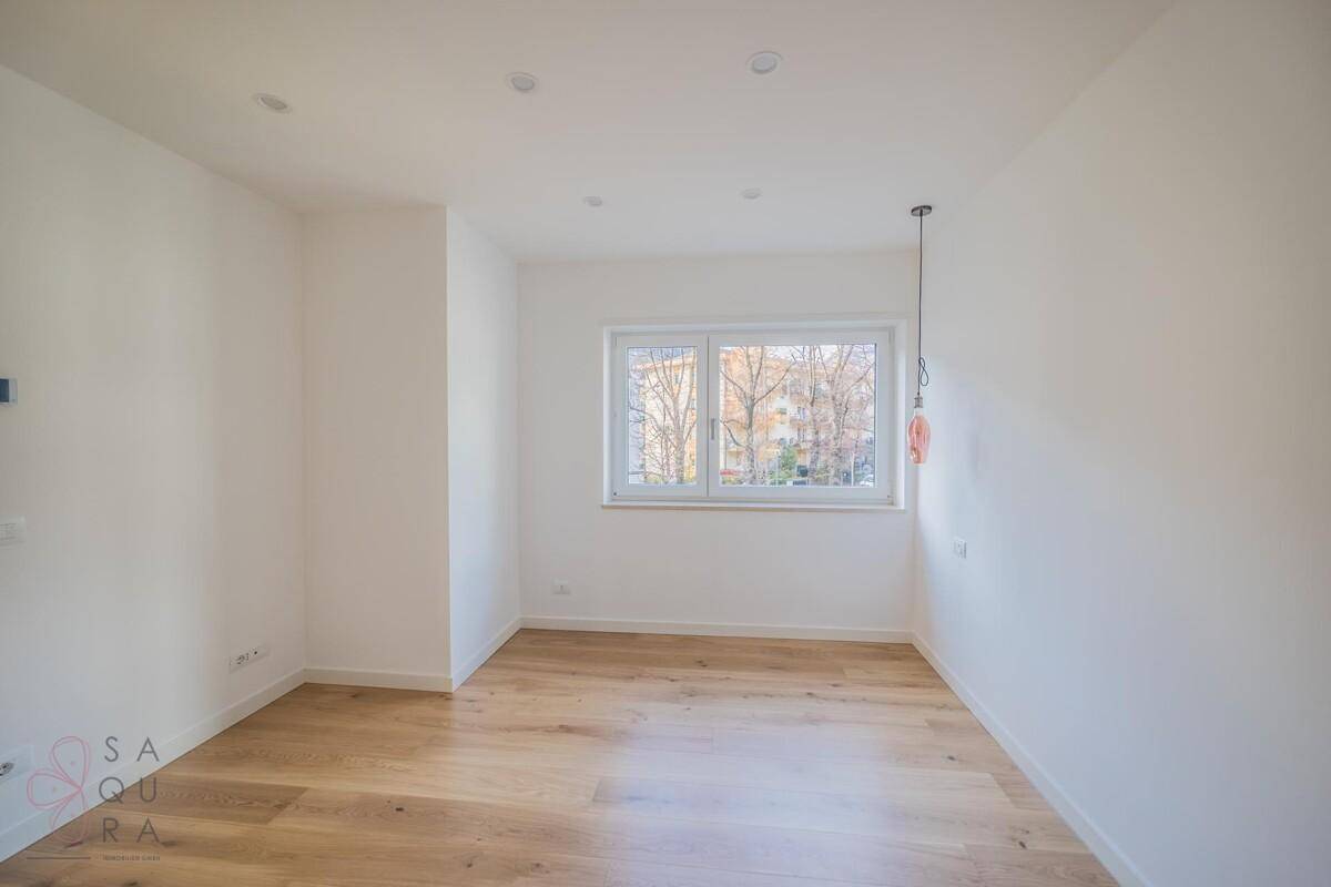 Helles Zimmer mit Holzboden und großem Fenster, das eine angenehme Atmosphäre schafft.
