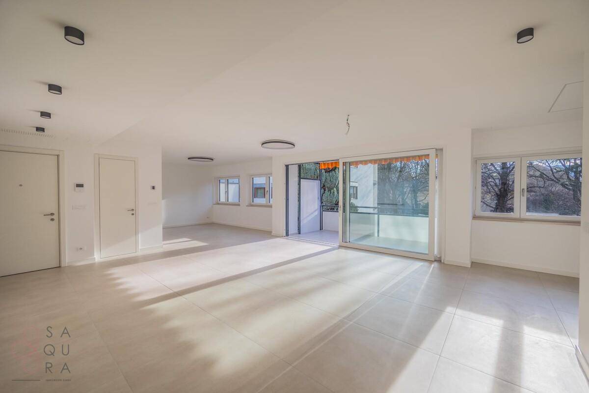 Heller Wohnraum mit Zugang zum Balkon und mehreren Türen zu angrenzenden Zimmern.