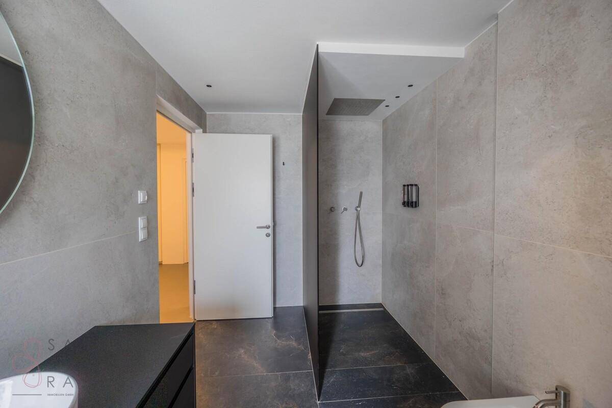 Elegantes Badezimmer mit begehbarer Dusche und modernen grauen Fliesen, minimalistisch gestaltet.