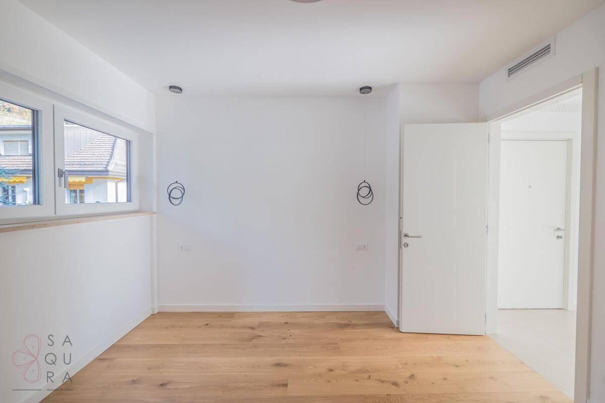 Helles Zimmer mit Holzboden und Fenster, das viel Tageslicht hereinlässt.