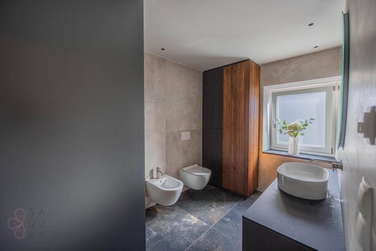 Modernes Badezimmer mit Bidet, WC, Einzelwaschbecken und Fenster für Belüftung.