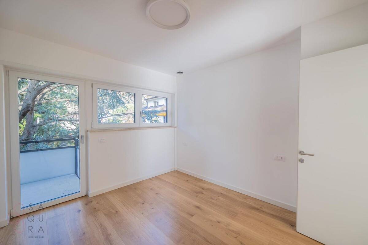 Helles Schlafzimmer mit Holzboden und Zugang zum Balkon, bietet eine angenehme Atmosphäre.