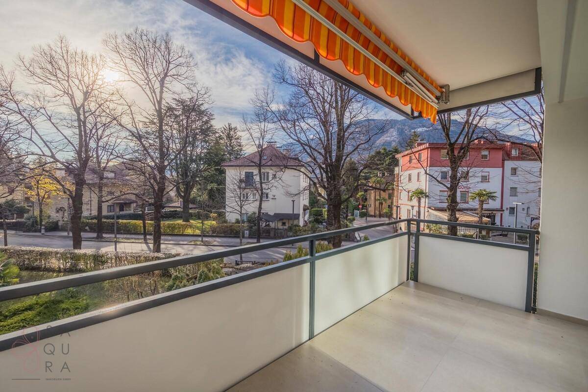 Geräumiger Balkon mit Markise und Blick auf die grüne Umgebung und die Stadt.