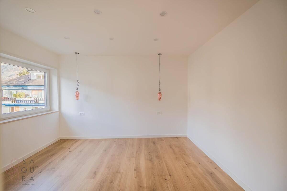 Geräumiges Zimmer mit Holzboden und modernen Hängelampen, bereit zur individuellen Gestaltung.