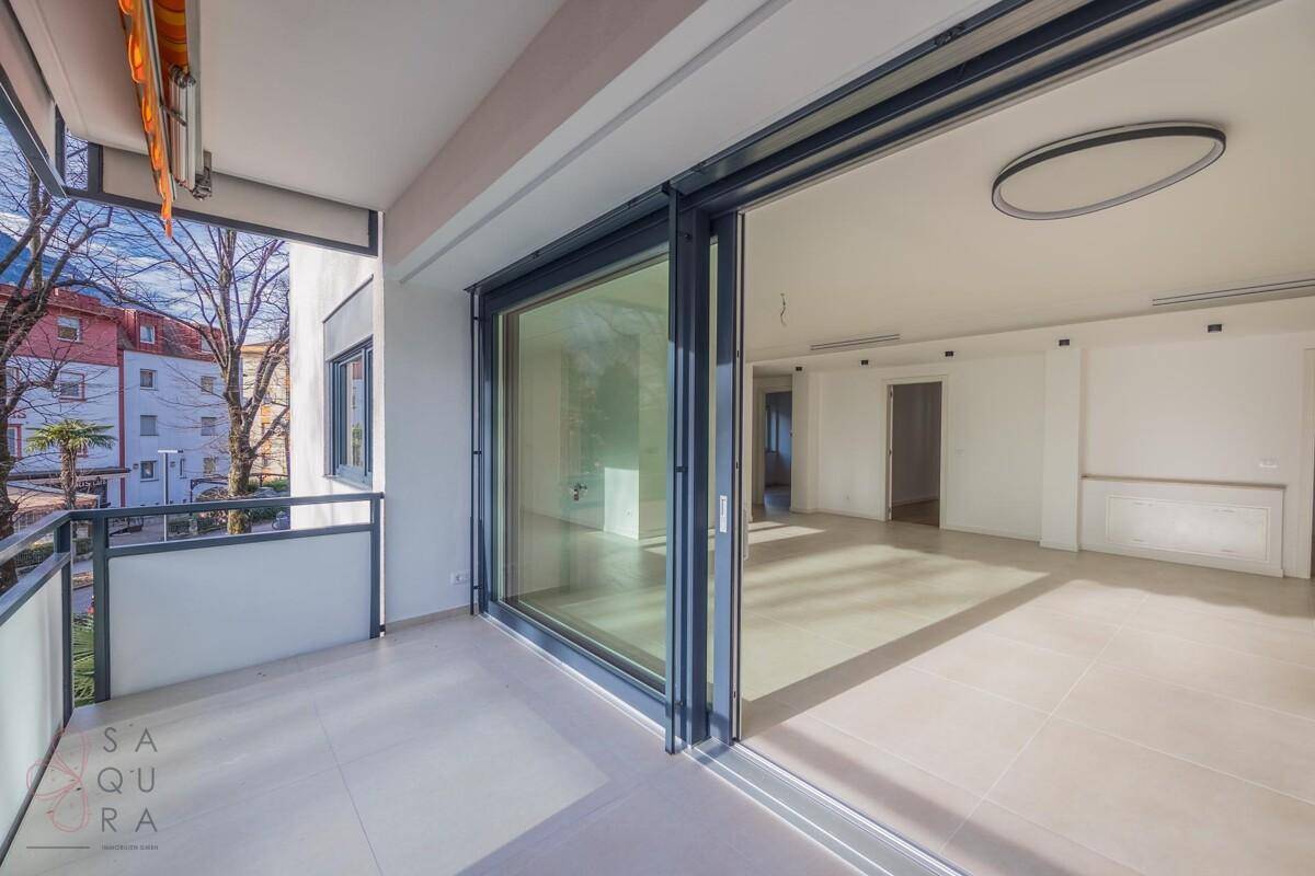Blick vom Wohnzimmer auf den Balkon mit Markise und umliegender Wohnbebauung.