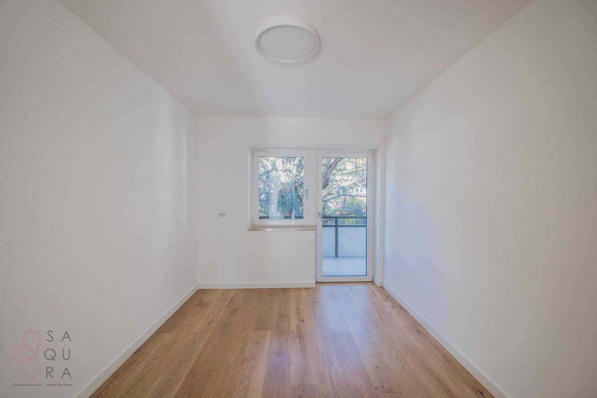 Helles Schlafzimmer mit Holzboden und Zugang zu einem kleinen Balkon, ideal für Ruhe.