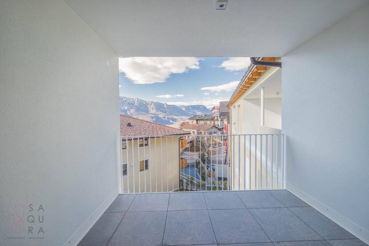 Geräumiger Balkon mit Fliesen und Panoramablick auf die Berge und die darunter liegende Nachbarschaft.