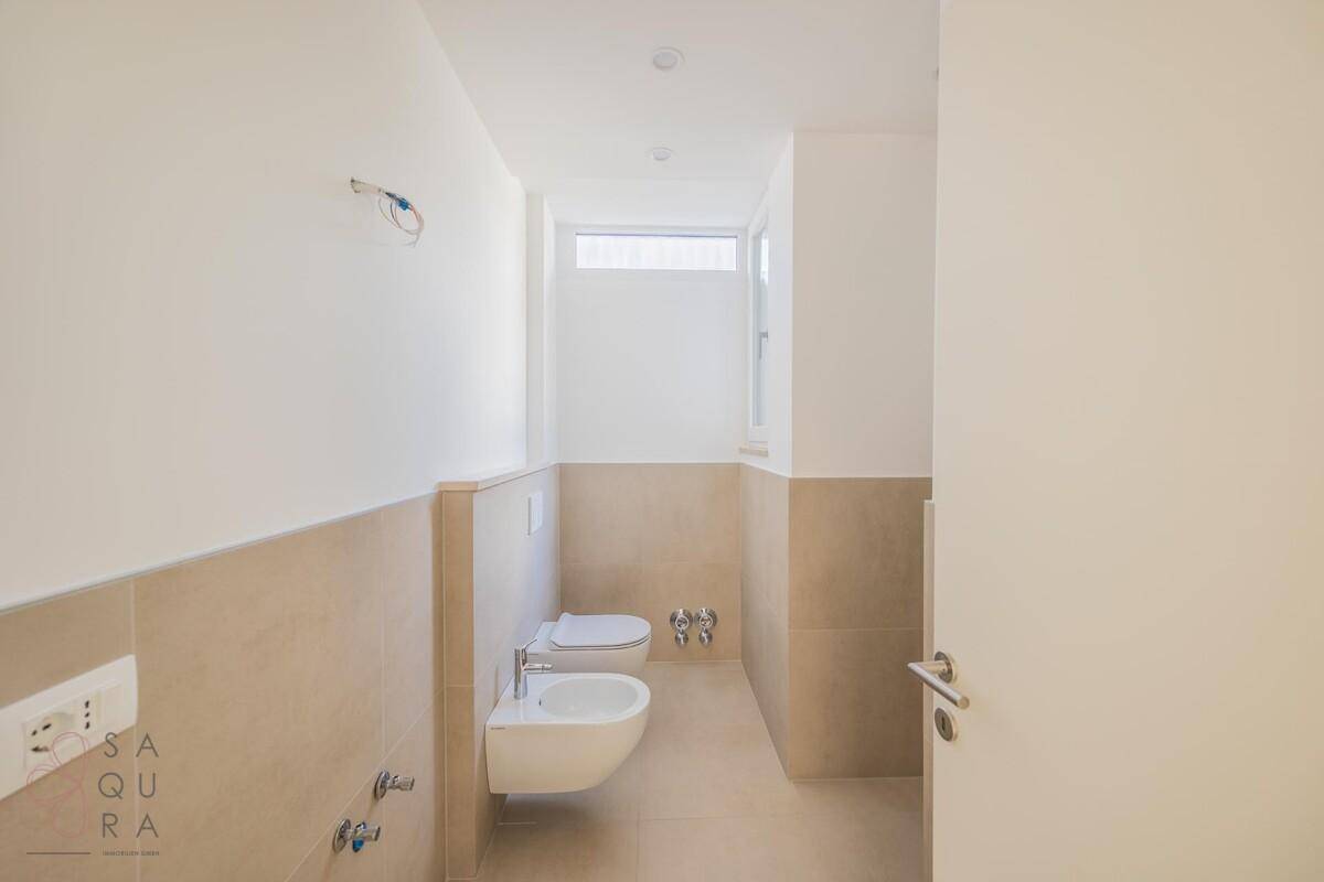 Helles Badezimmer mit Dusche, Bidet und Fenster für natürliche Belüftung.