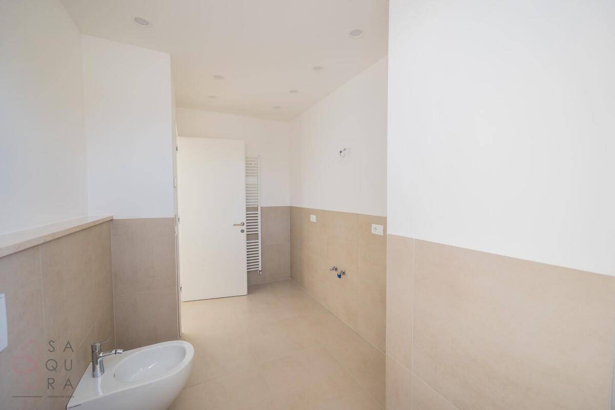 Geräumiges Badezimmer mit beigefarbenen Fliesen, beheiztem Handtuchhalter und viel Platz.