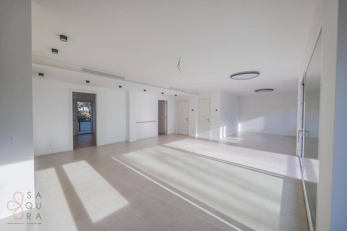 Weitläufiger, heller Wohnraum mit modernen Deckenleuchten und viel natürlichem Licht.