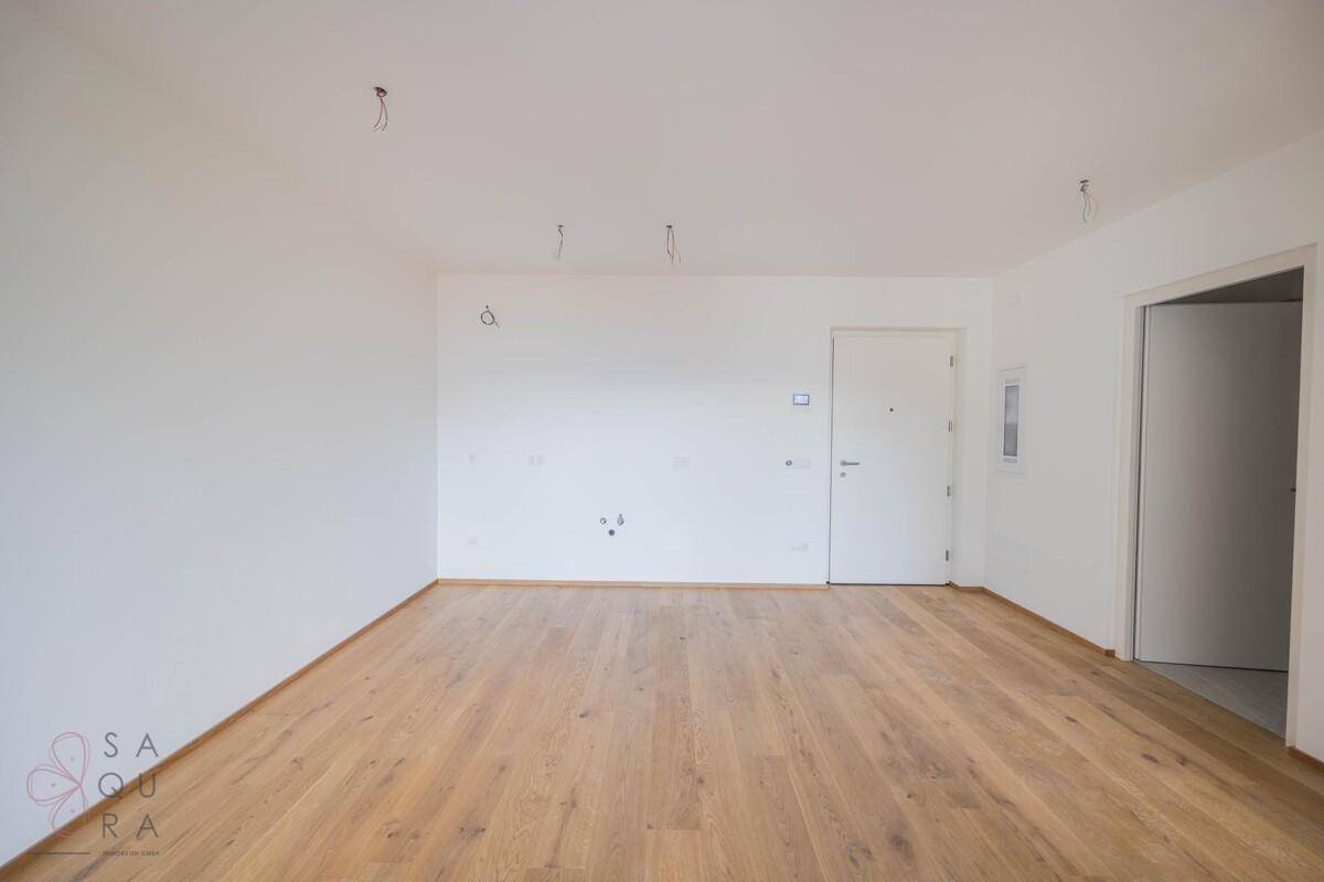 Leerer Raum mit Holzboden und weißer Eingangstür, bereit für die individuelle Gestaltung.