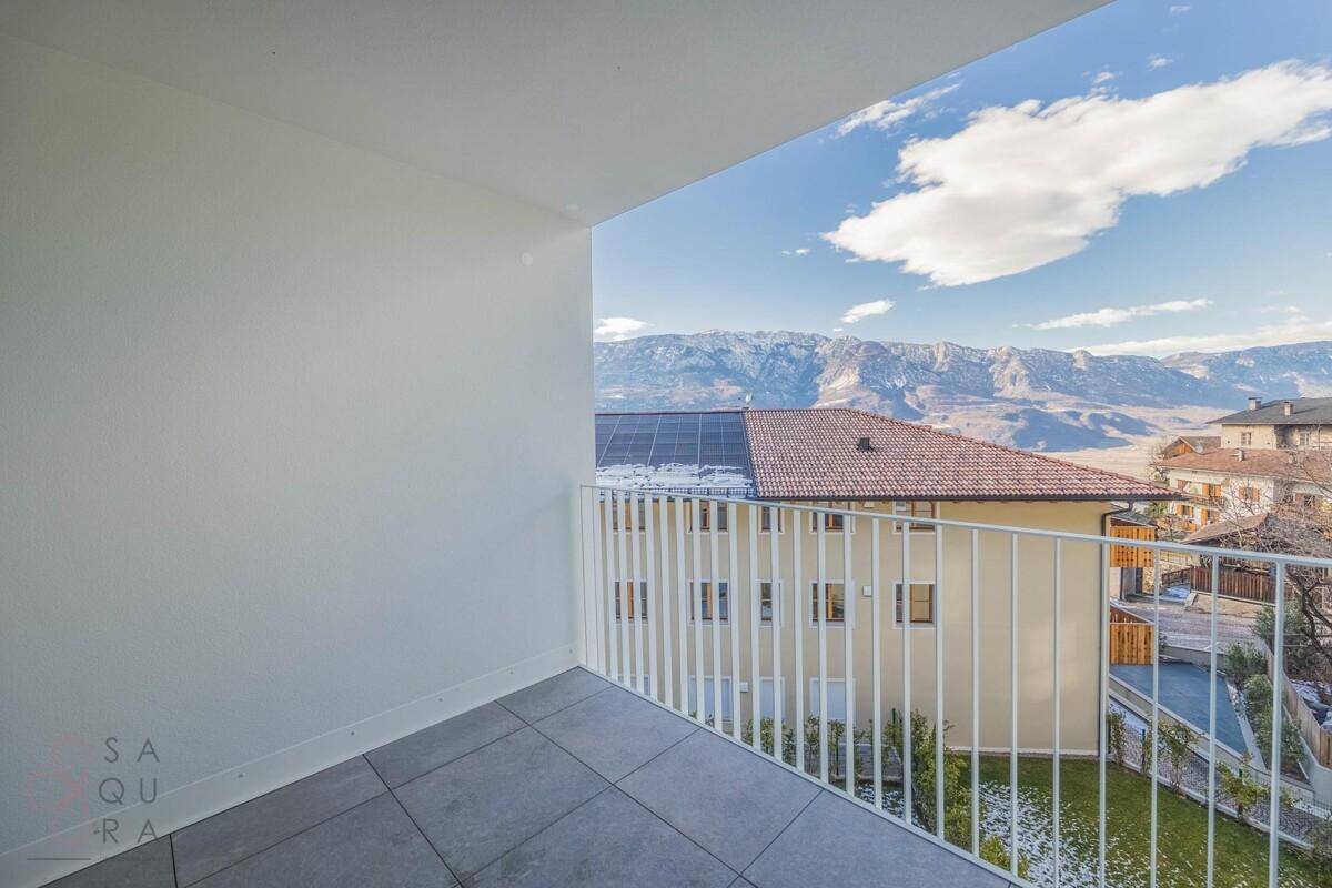 Balkon mit Fliesenboden und weißem Geländer, bietet einen weiten Blick auf die umliegende Berglandschaft.