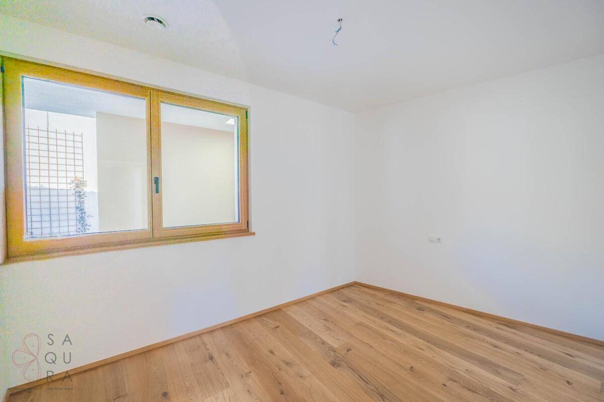 Schlafzimmer mit Holzboden und großem Fenster, das viel natürliches Licht in den Raum bringt.