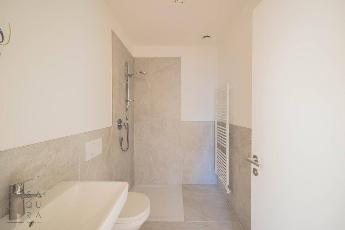 Modernes Badezimmer mit Dusche, Waschbecken und WC, ausgestattet mit hellen Fliesen.