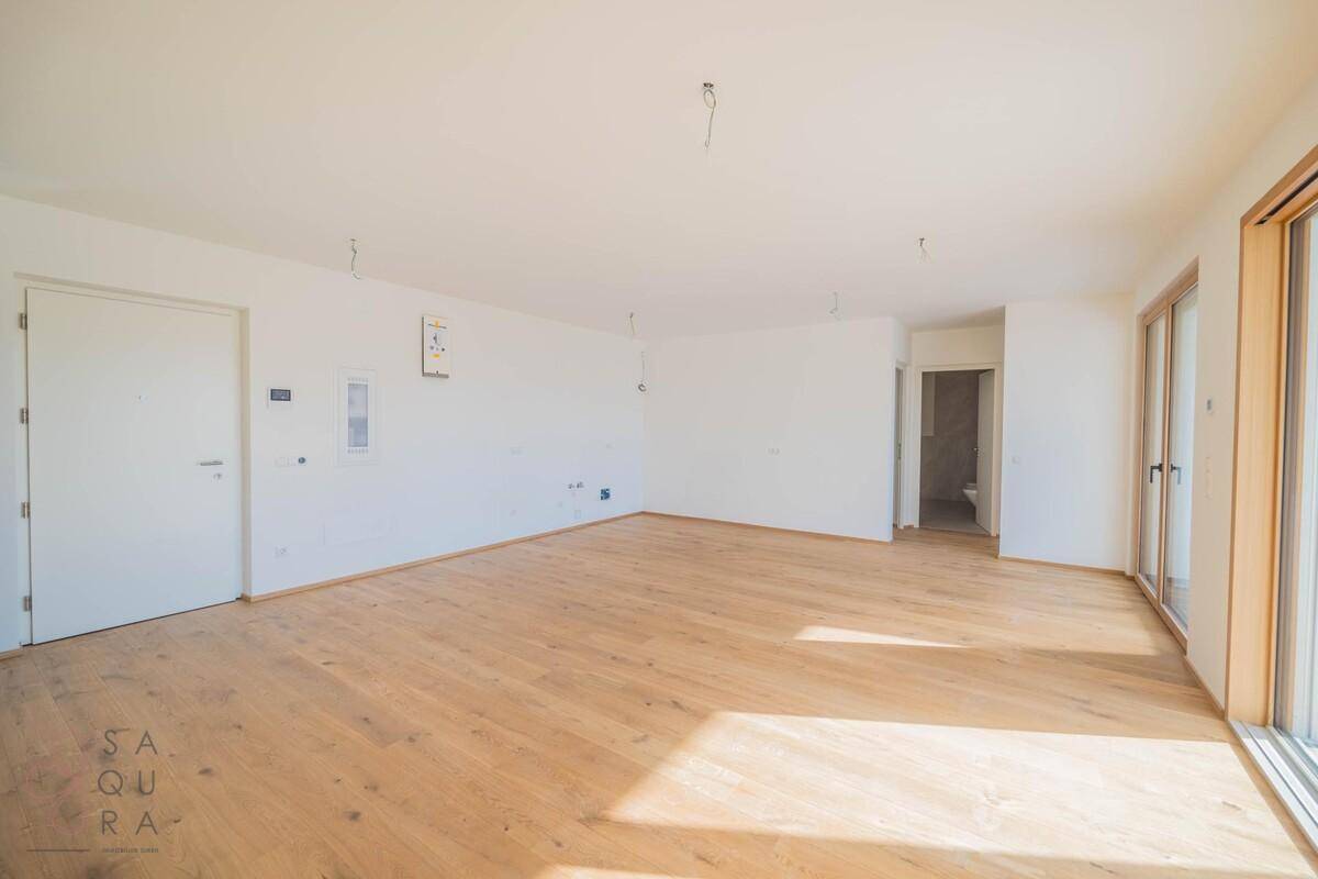 Leerer Wohnraum mit Holzboden und Zugang zu einem Badezimmer, bereit für individuelle Gestaltung.