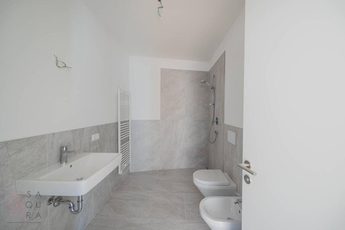 Helles Badezimmer mit Dusche, Waschbecken, WC und Bidet, modern gefliest.