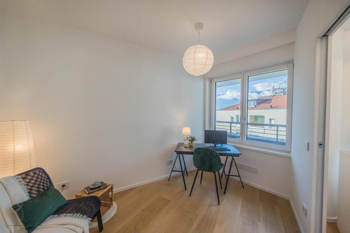 Ruhiges Arbeitszimmer mit Holzboden, Schreibtisch und Fenster mit Blick auf die Stadt.