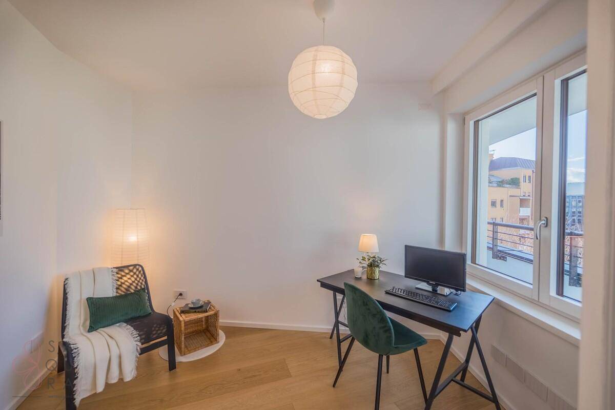 Helles Arbeitszimmer mit Schreibtisch, Stuhl und großem Fenster, das viel Tageslicht hereinlässt.